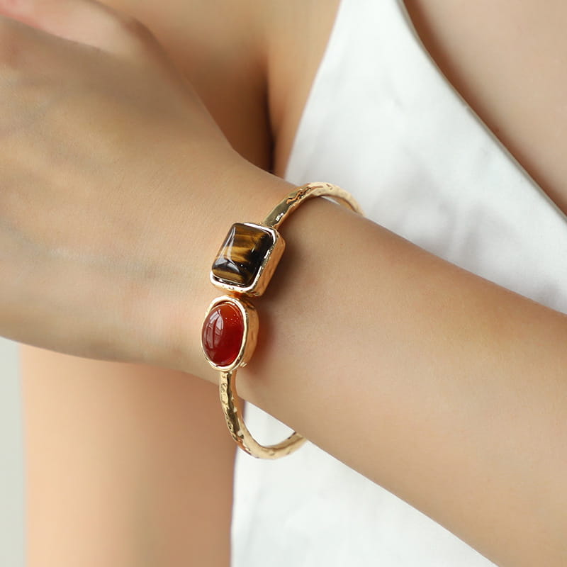 Vintage hammered gold bangle featuring a textured metal band with rectangular tiger’s eye and oval carnelian gemstone accents.
