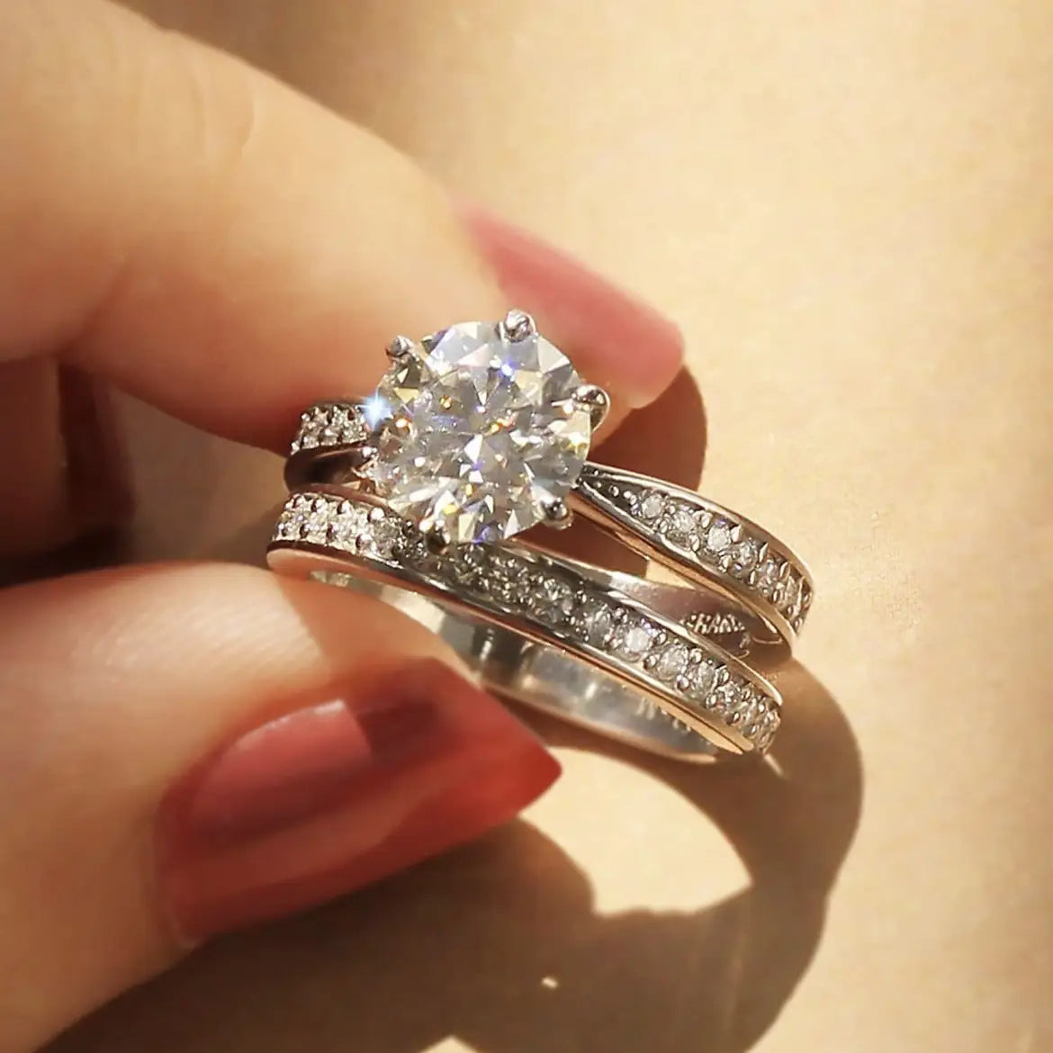 A sparkling round cut zircon wedding ring set with a central stone and intricate band detailing in white gold finish.
