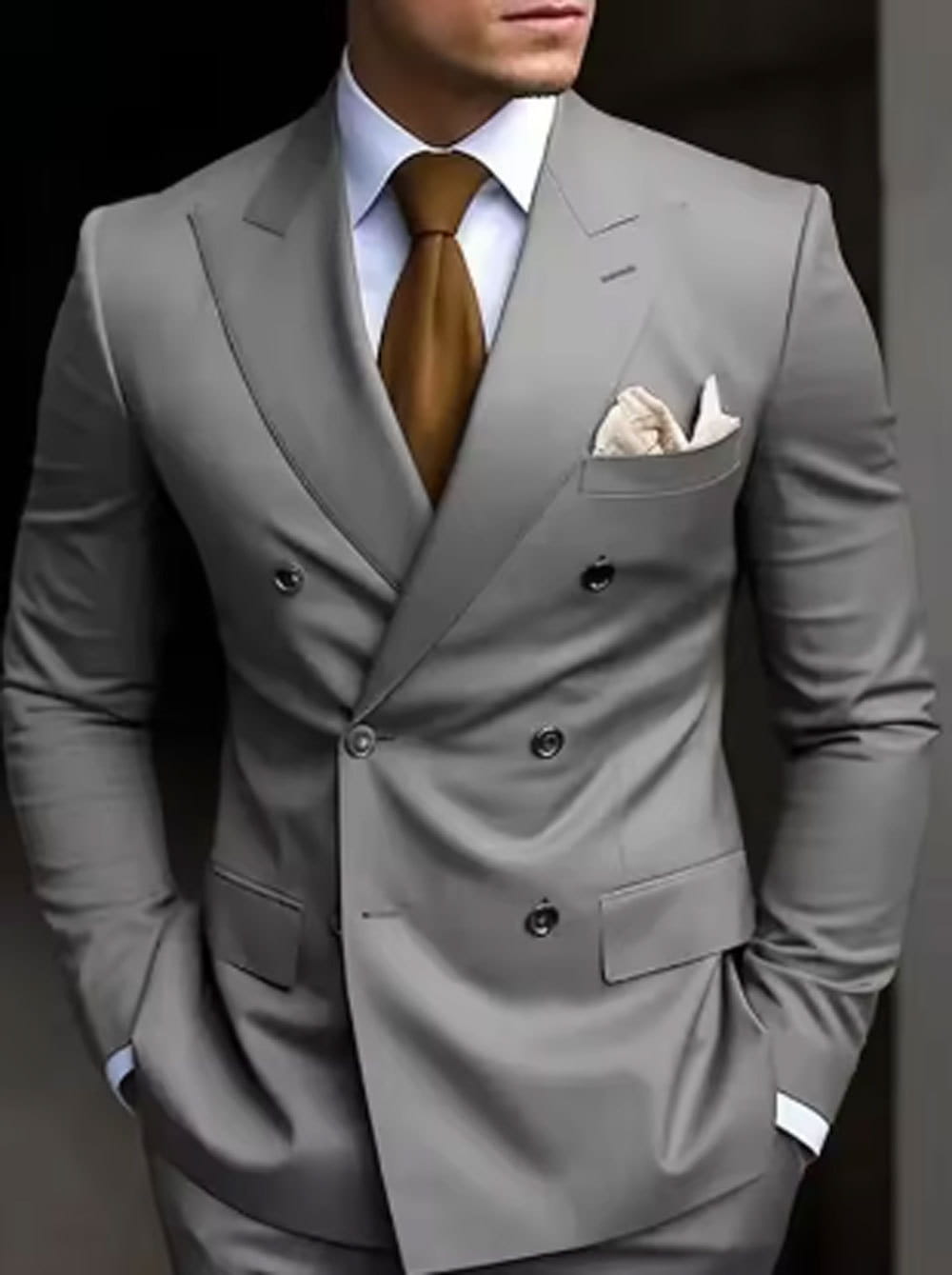 Chaqueta de traje cruzado doble de corte entallado para hombre, confeccionada en gris a medida, con botones negros y un pañuelo de bolsillo a juego.