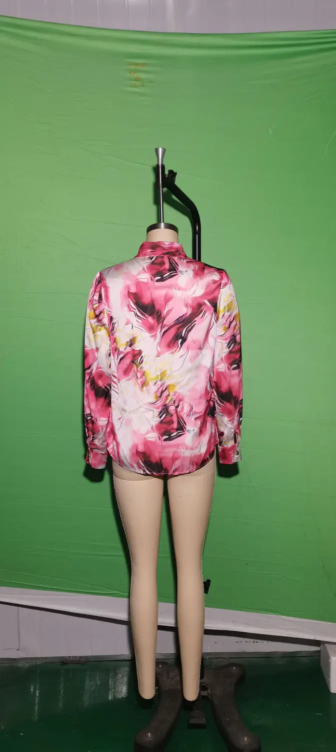 A vibrant pink and white floral patterned women’s marble print satin long sleeve button blouse displayed on a mannequin.
