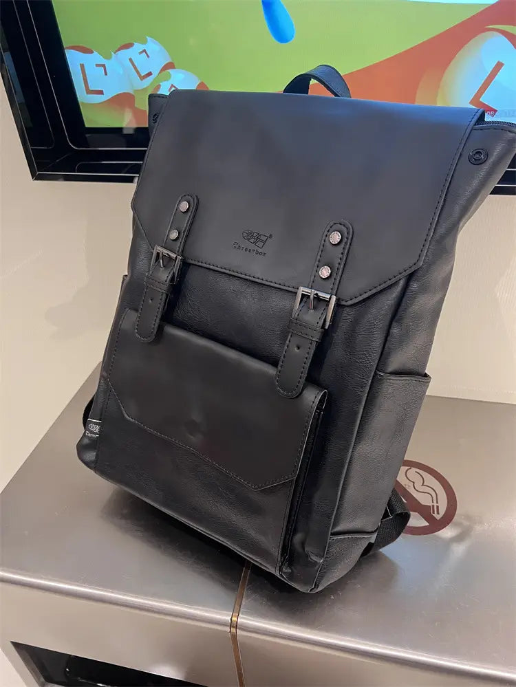 Black leather vintage college backpack with silver-toned metal buckles and a subtle brand logo on the front flap designed for large capacity travel use.