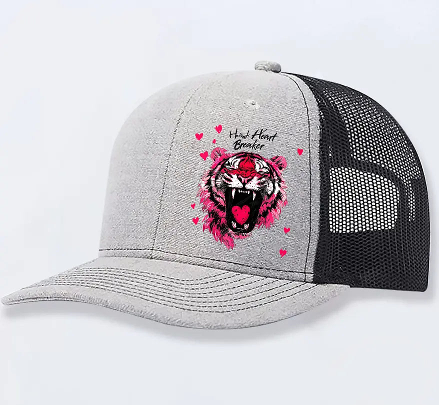 Gray and black trucker hat featuring a vibrant pink tiger graphic and heart breaker text above it in tan color for men.