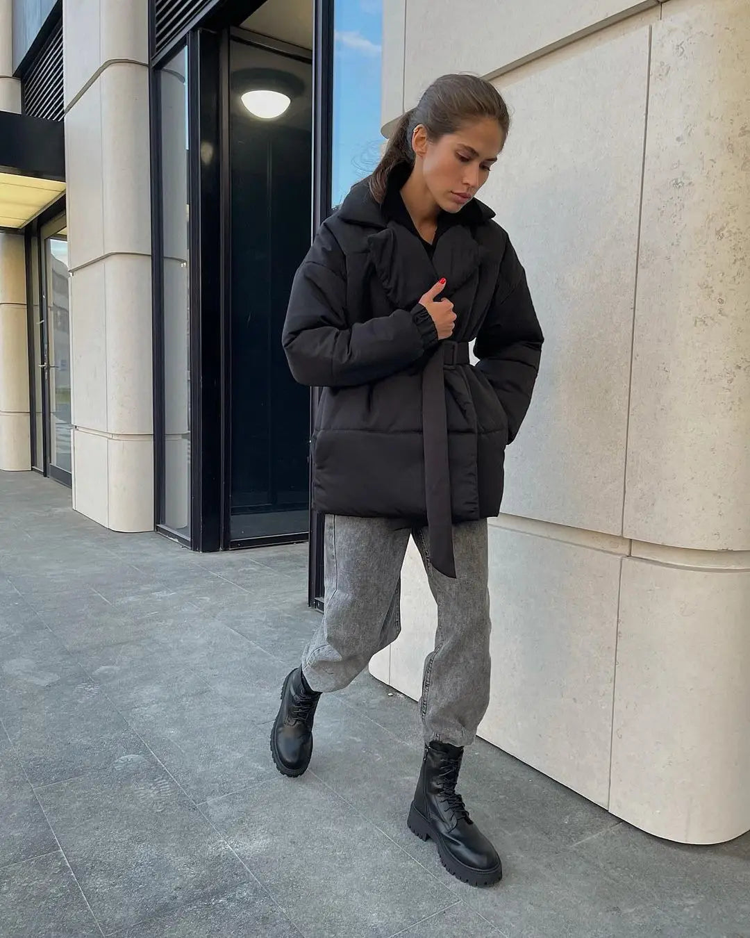 Damen-Schwarze Gurtsteppjacke mit Kapuze, wattierte Pufferjacke für den Winter, von der Rückansicht dargestellt, mit Gürtel und Steppdesign.