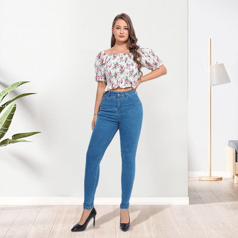 Woman wearing high waist stretch skinny jeans in blue paired with a white floral off-the-shoulder top with short puffed sleeves.