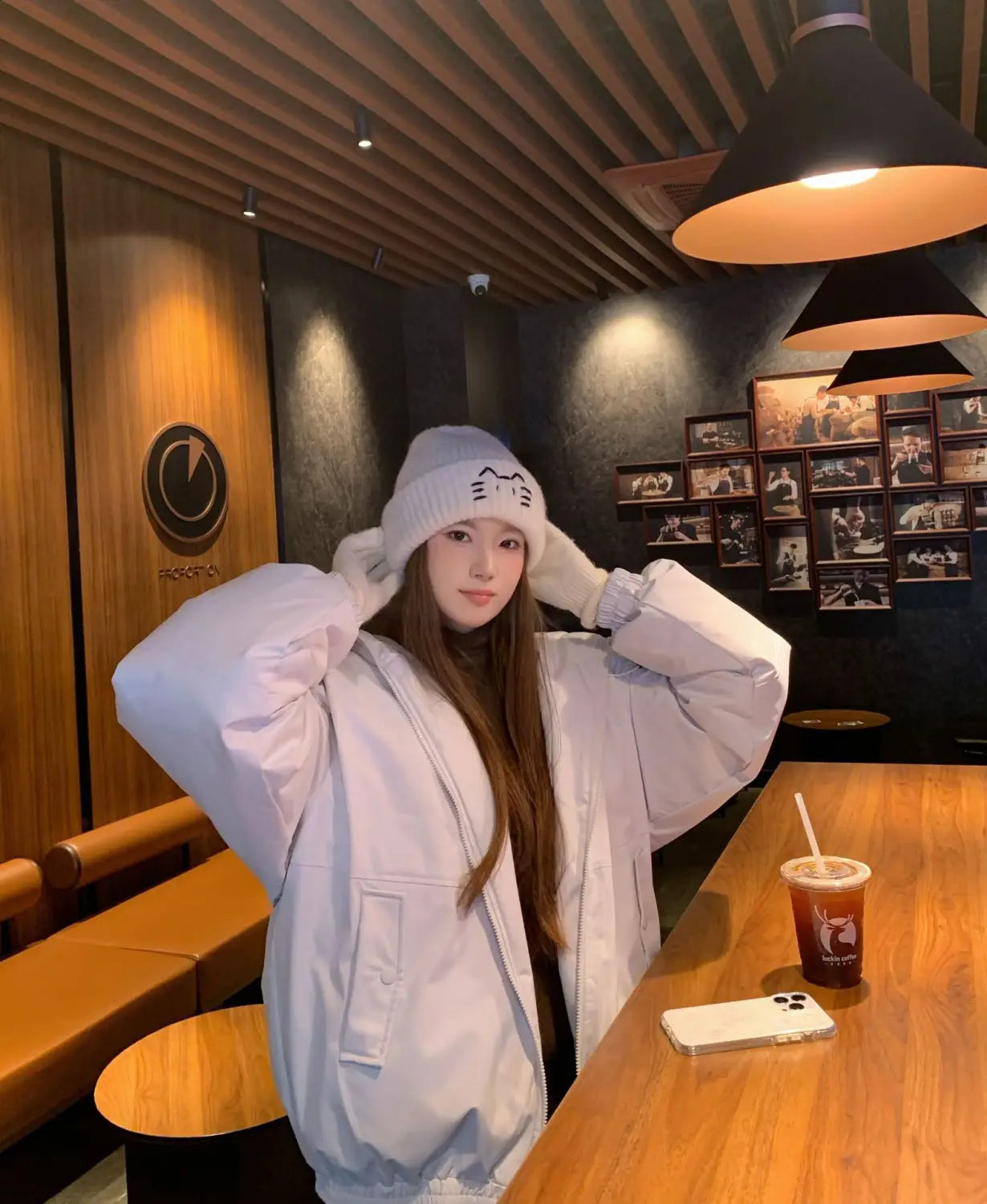 White puffer jacket with a relaxed oversized fit and subtle front pockets shown from the back side, paired with a cat embroidered knitted beanie hat.