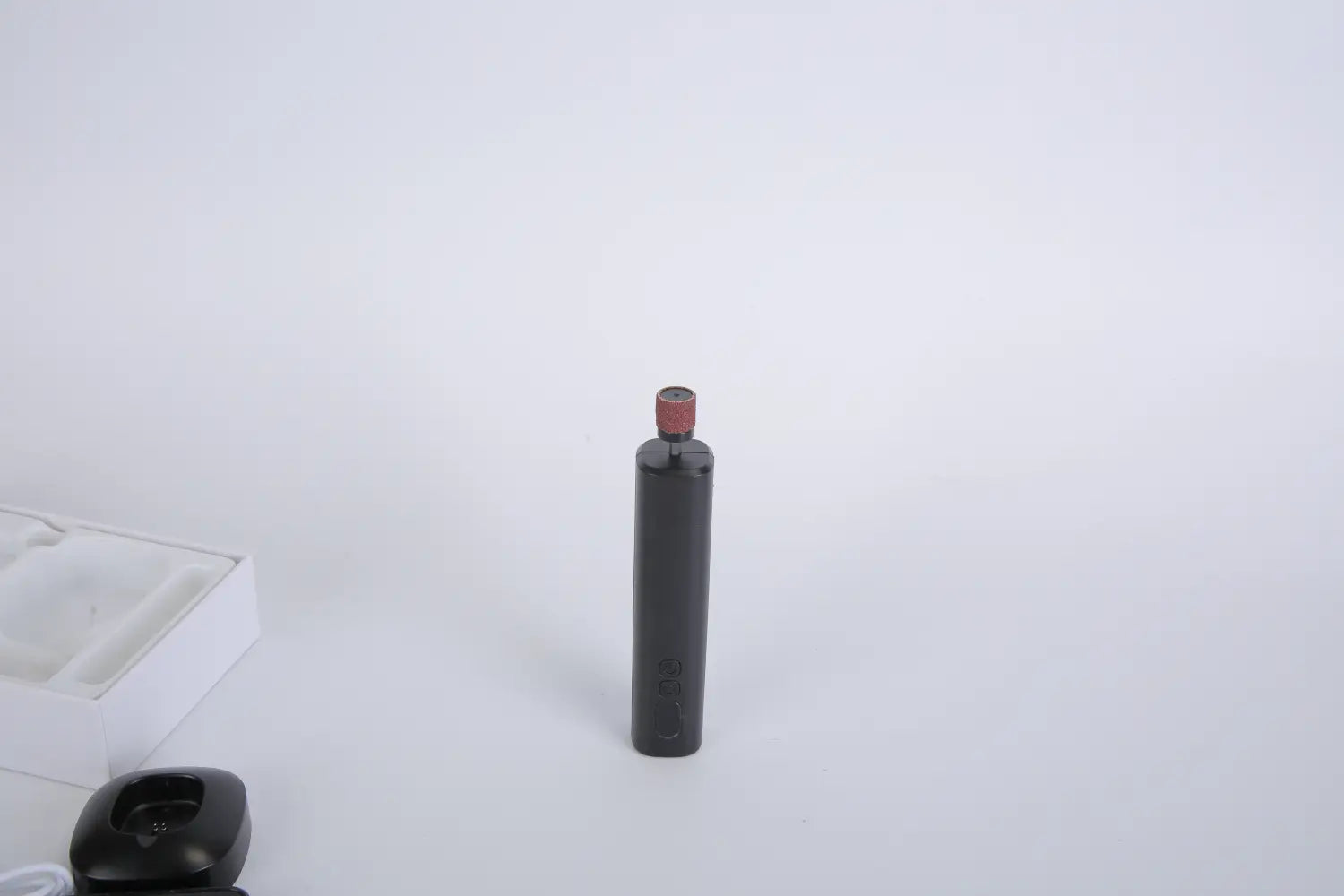 black cylindrical vape pen with a red cap displayed as part of an electric foot callus remover and nail grinder kit