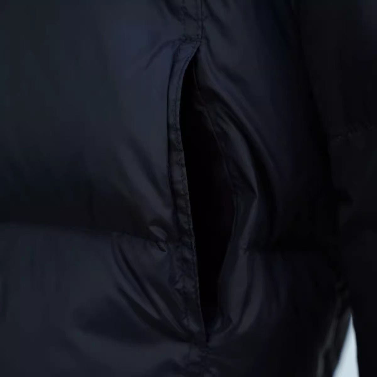 Chaqueta acolchada de plumón negra con una cremallera parcialmente abierta que deja ver el forro interior, presentada como parte de la colección de chaquetas de invierno acolchadas de plumón moradas para mujer.