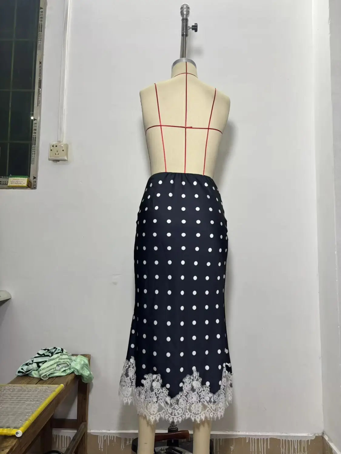 Jupe midi en satin bleu marine avec pois blancs et une délicate bordure en dentelle au bas.