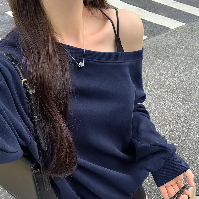 Navy blue women’s loose off shoulder ribbed knit sweater with long sleeves and ribbed cuffs shown from the back side.