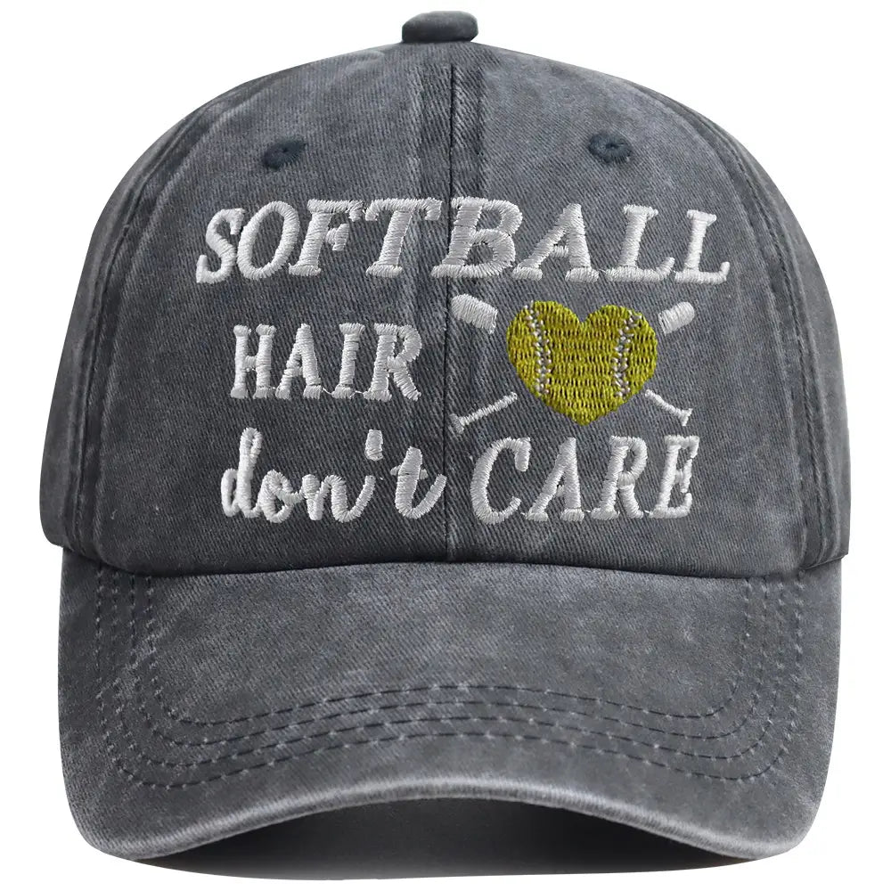 A faded gray distressed softball hair don’t care cap with white embroidered text and a yellow heart-shaped softball design.