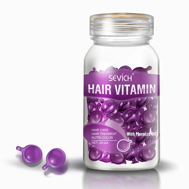Un frasco de vidrio transparente con una etiqueta morada que contiene 30 cápsulas translúcidas de vitamina para el cabello en color morado, diseñadas como pequeñas gotas redondeadas para la reparación y el brillo uniforme.