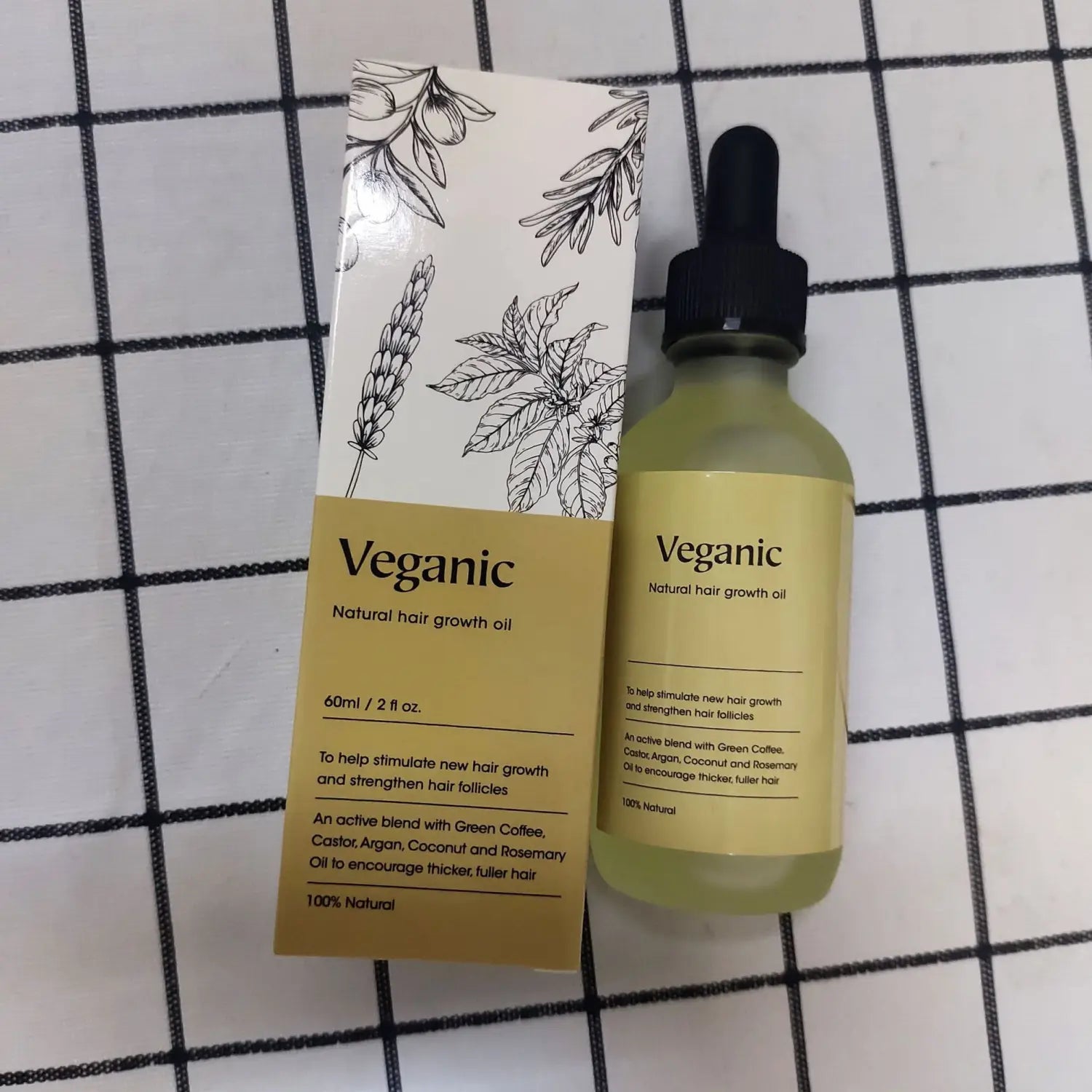 Veganic hair growth oil vegan natural essential treatment in a clear glass bottle with black dropper cap and beige label next to botanical-themed packaging.