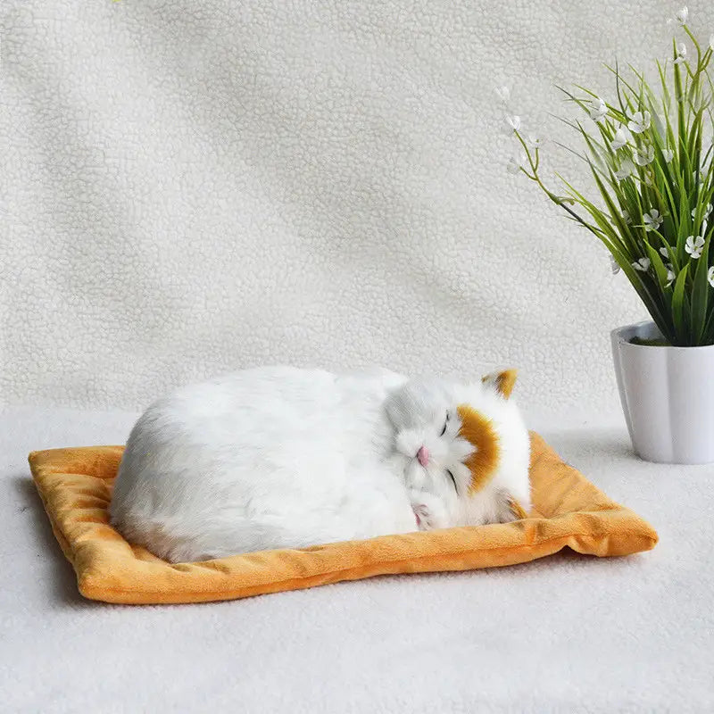 A fluffy white and orange realistic breathing plush cat figurine with closed eyes resting peacefully on a soft golden-orange plush pet bed.