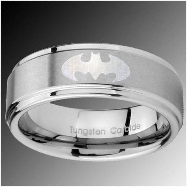 A sleek silver batman logo ring made of polished tungsten carbide with engraved detailing featured in a black tungsten wedding ring with green aluminum 8mm design.