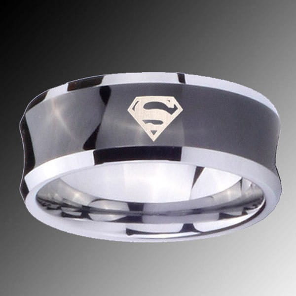 A sleek black tungsten wedding ring with green aluminum accents and a polished silver superman logo with a metallic finish.