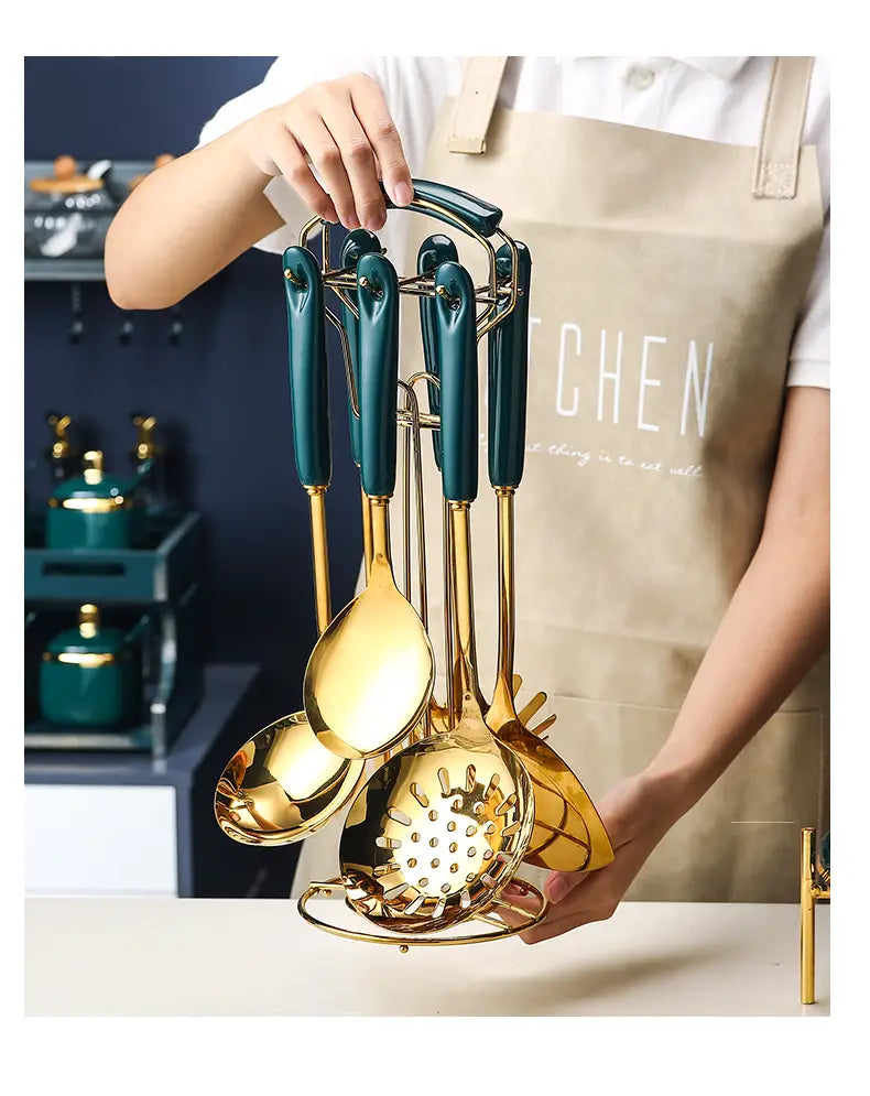 Set aus Edelstahl-Küchenutensilien in Gold- und Teal-Ausführung mit goldgetönten Köpfen und Teal-Griffen, ordentlich in einem passenden Ständer arrangiert