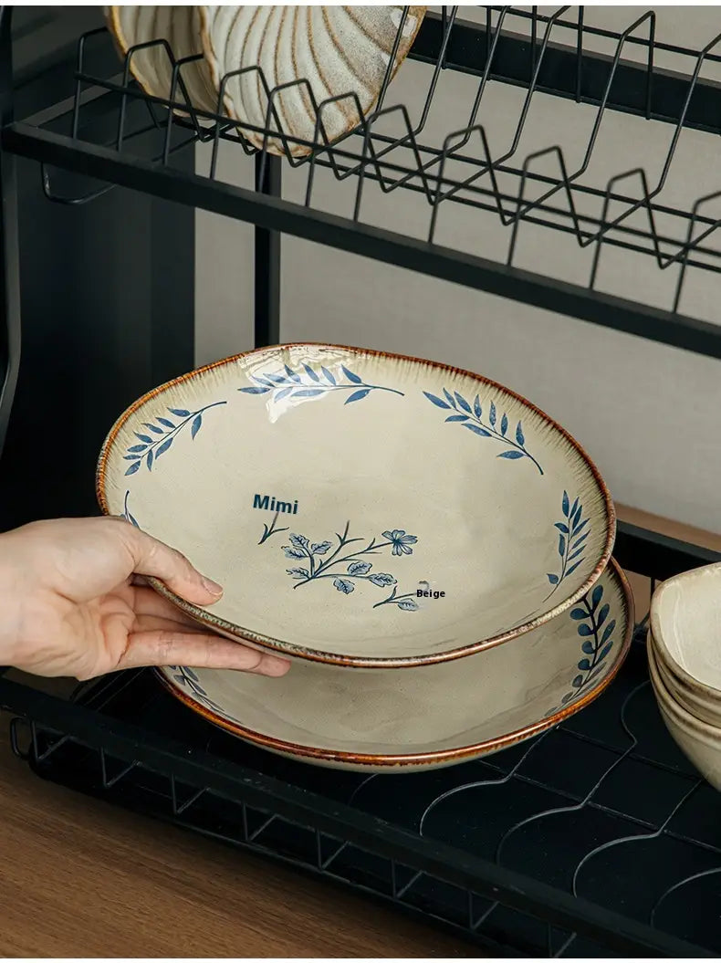 Cream-colored ceramic 9-inch deep plate with blue floral and leaf patterns, a rustic brown rim, and mimi printed near its center.