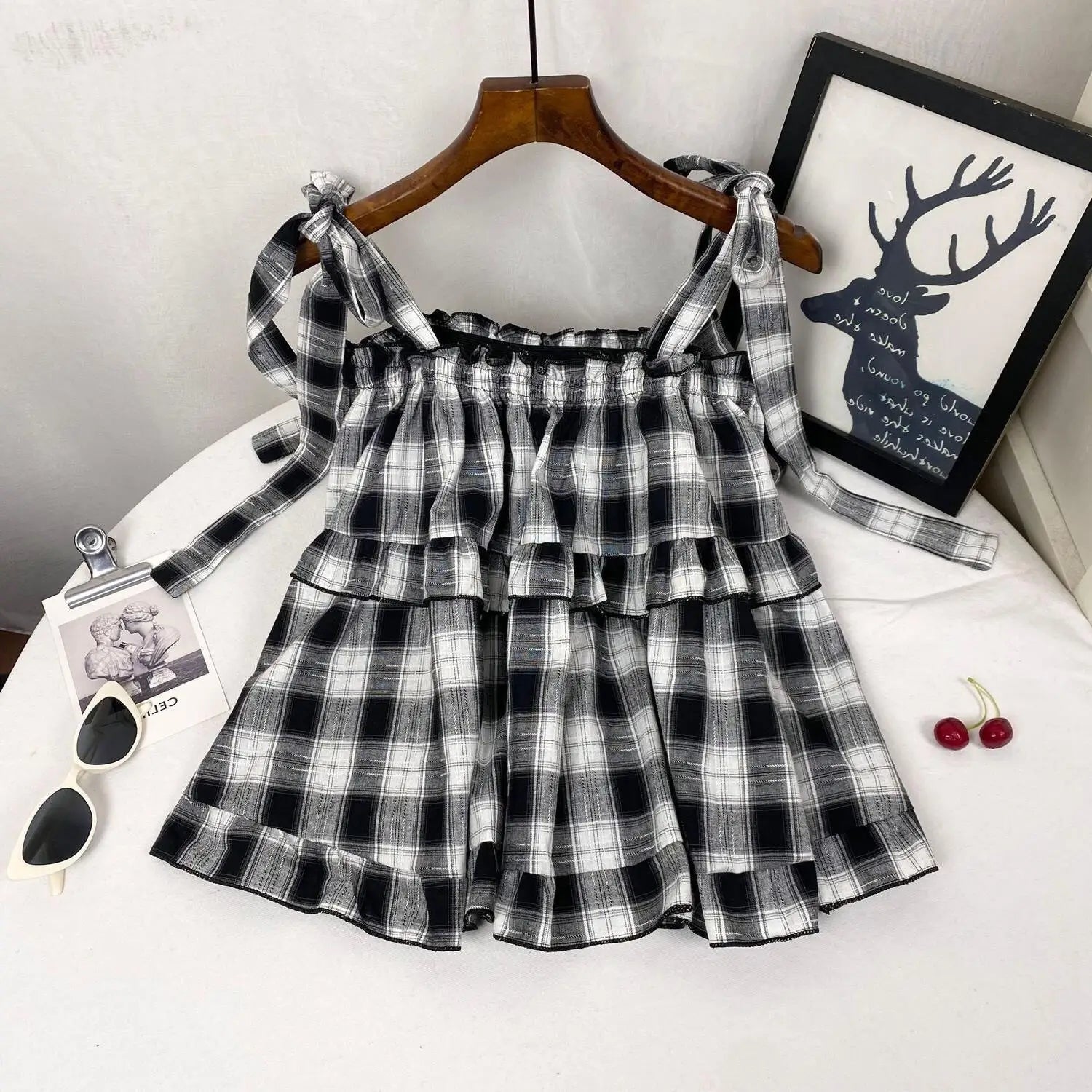 Black and white plaid tiered mini dress with ruffled bow straps in lightweight fabric ideal for casual wear
