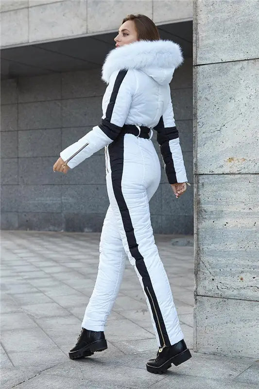 Combinaison de ski à capuche en fourrure matelassée pour femmes, blanche, avec des rayures verticales noires, présentant un design de type doudoune et une capuche en fourrure blanche duveteuse doublée de fourrure.