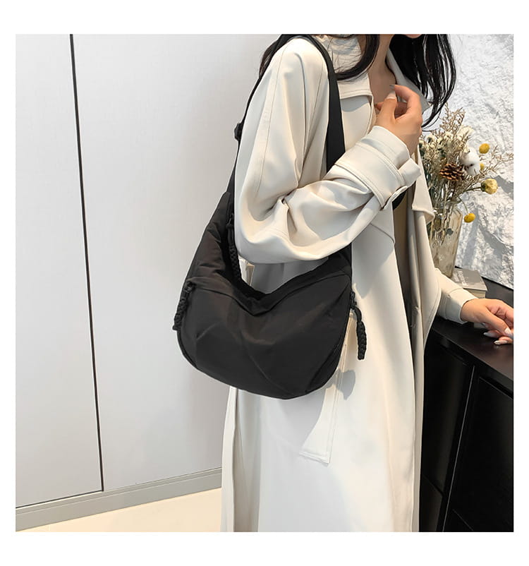 Black nylon crossbody bag with large capacity hobo shoulder design and drawstring closure featuring a subtle textured finish.