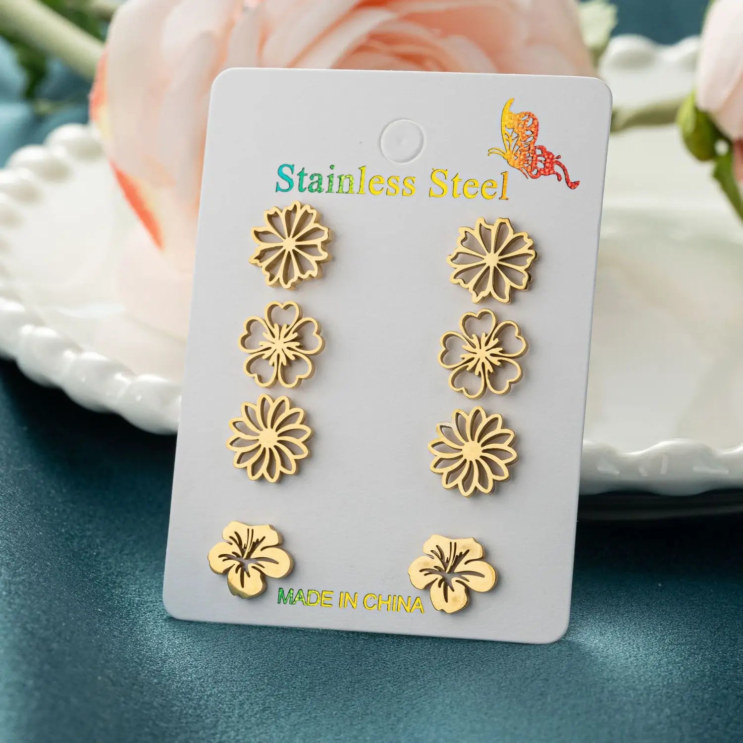 Boucles d’oreilles à clous en acier inoxydable de couleur dorée, en forme de fleur, présentées sur une carte blanche, issues d’un ensemble de 6 boucles d’oreilles à clous en acier inoxydable à motif floral.