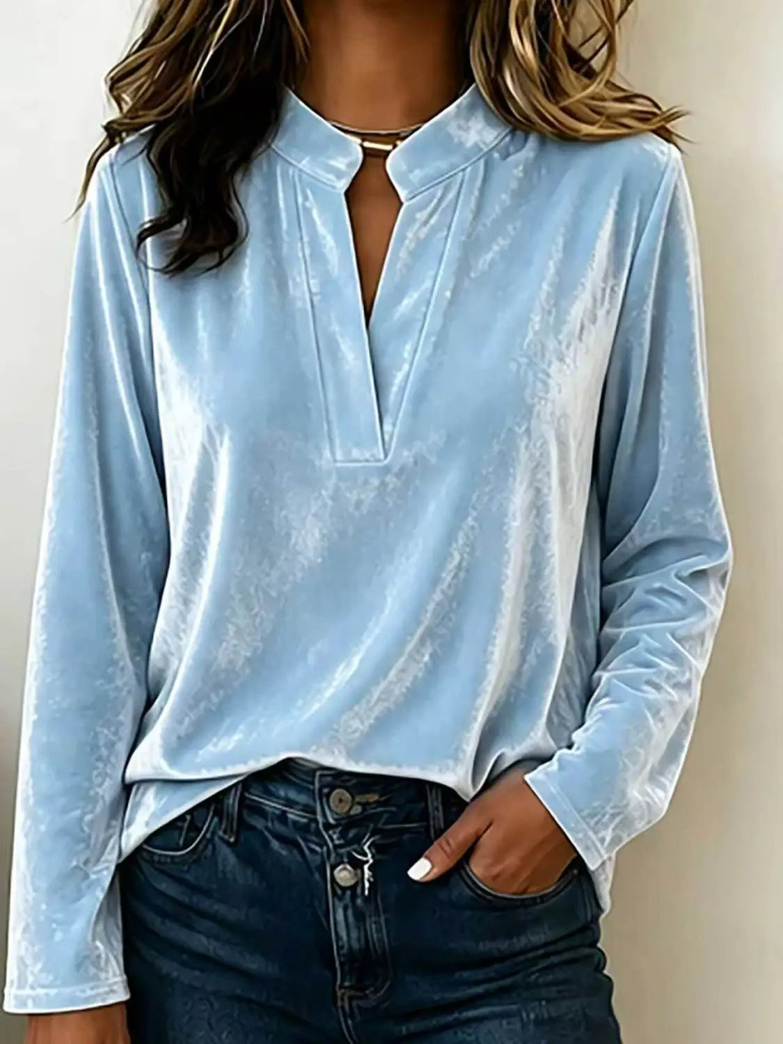 Eine hellblaue Samtbluse mit langen Ärmeln für Damen mit einem Mandarin-Kragen und einer Knopfleiste mittig vorn.