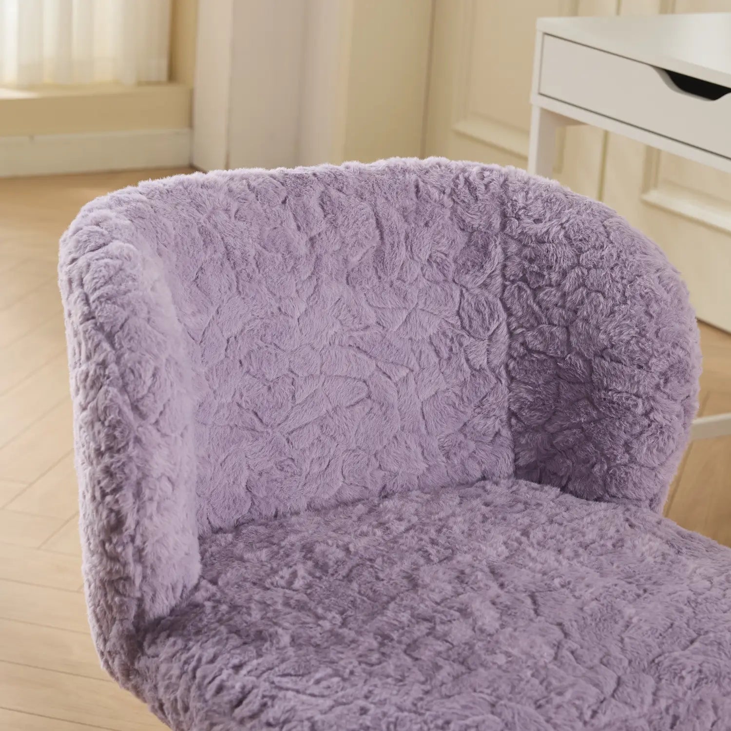 Un fauteuil de bureau en fausse fourrure lavande, rembourré, avec des roues colorées, présentant une surface souple texturée et des contours arrondis.