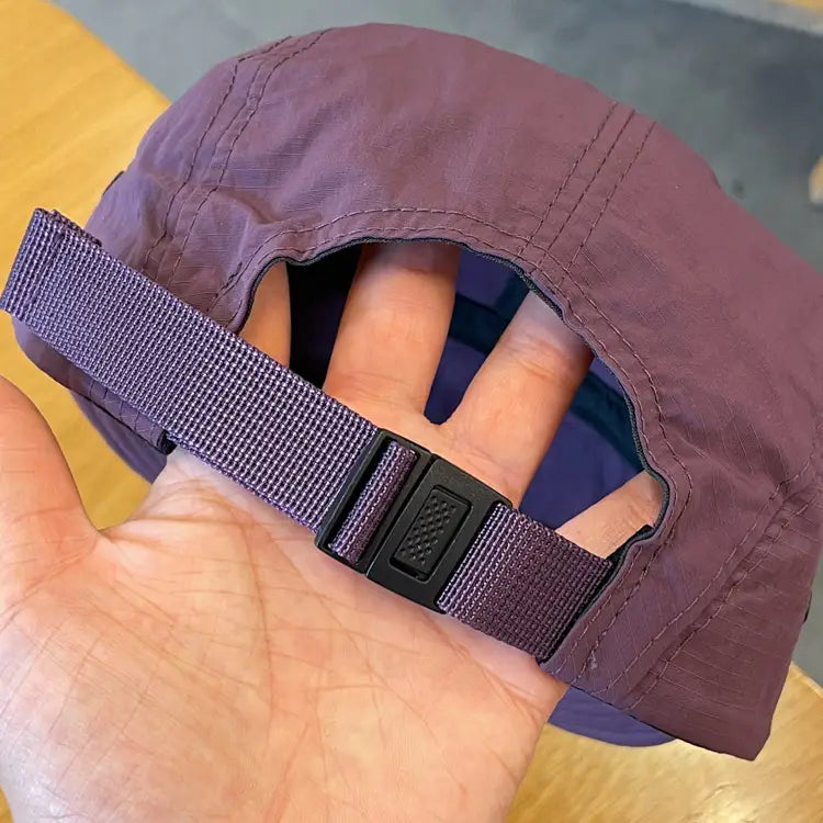 back view of a purple quick drying short brim five panel cap with adjustable strap and black plastic buckle