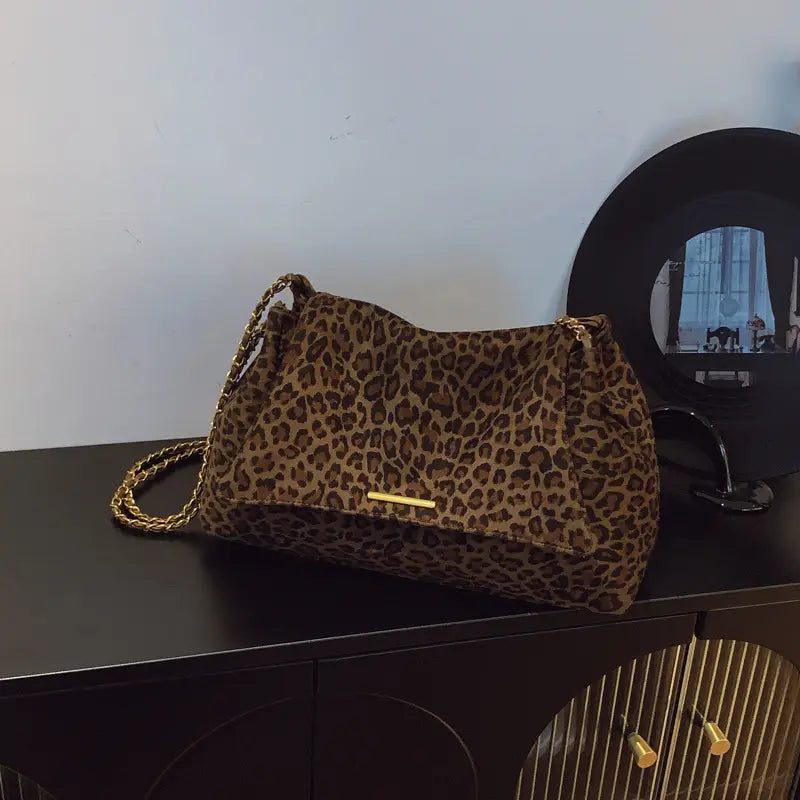 A leopard print crossbody bag featuring a gold chain strap and metallic clasp.