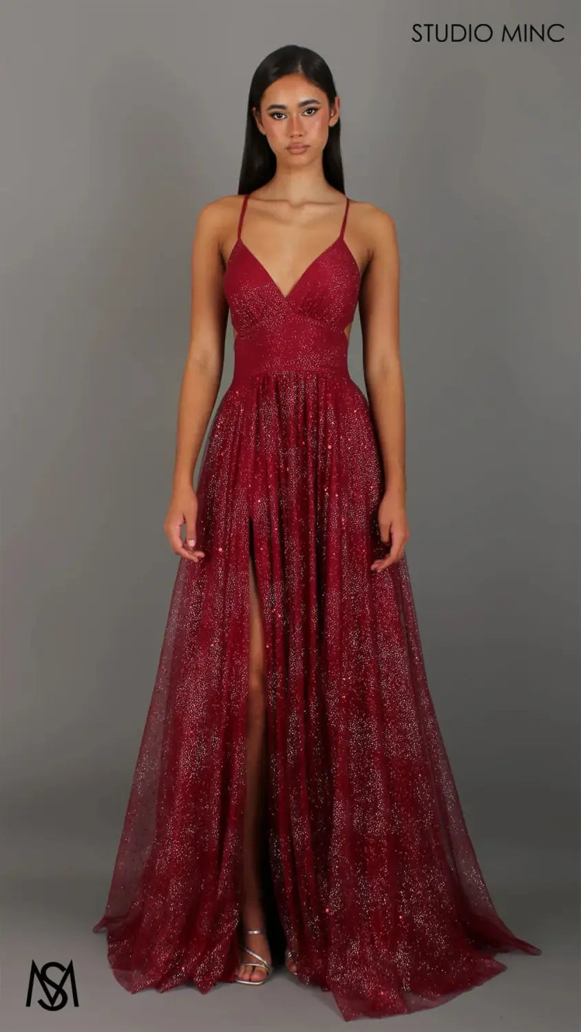 A shimmering burgundy floor-length evening gown with a v neckline and thin spaghetti straps made from glittery mesh fabric.