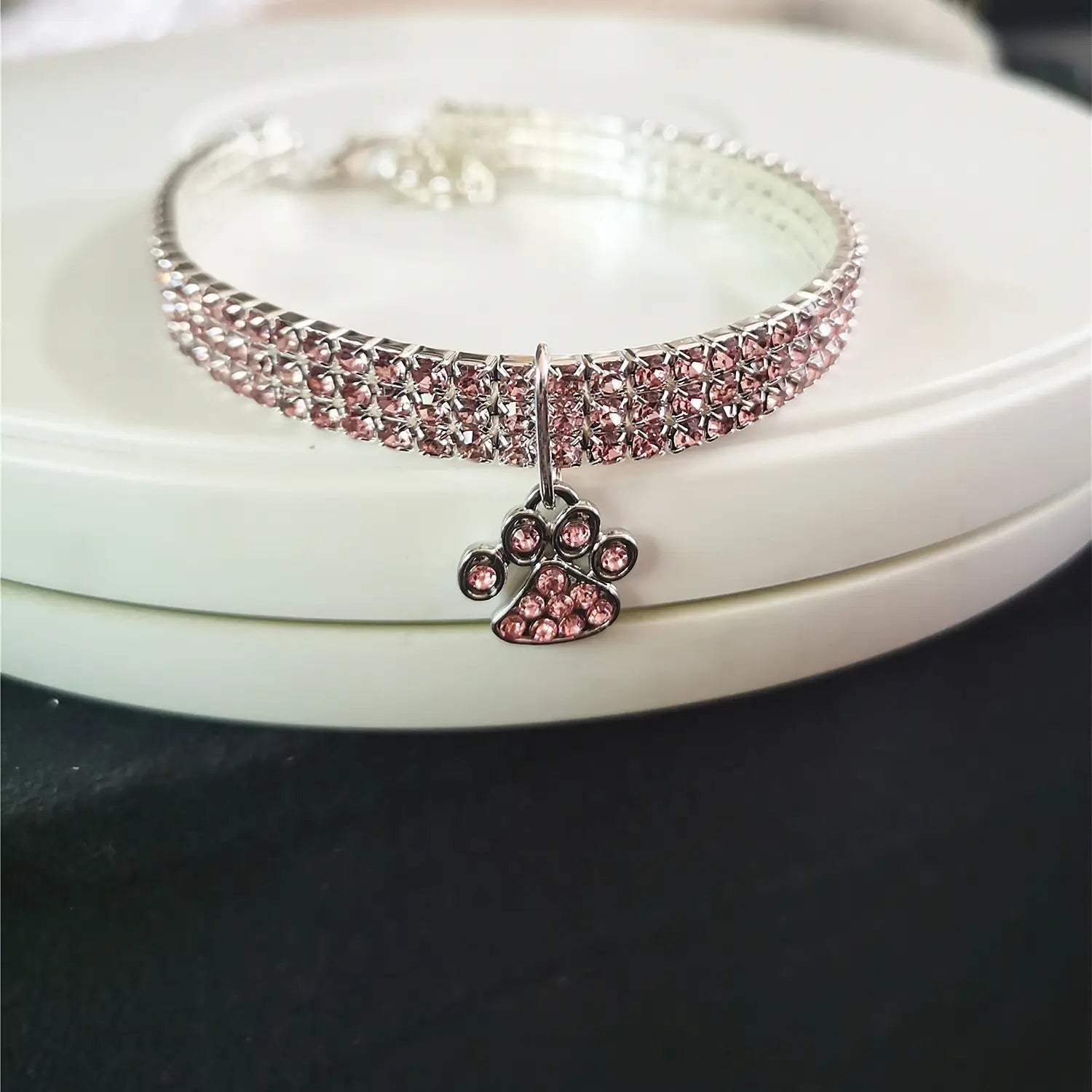 Un collier pour animal de compagnie en strass roses scintillant avec un charme assorti en forme de patte, conçu pour les chiens.