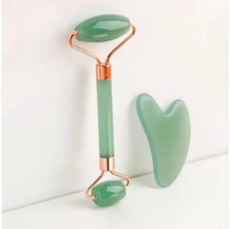 A natural resin jade roller and gua sha facial massage set featuring a jade green stone roller with rose gold metal accents and a matching heart-shaped gua sha tool.
