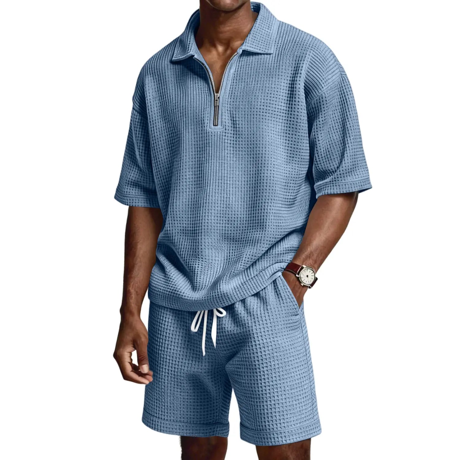 Ensemble deux pièces bleu clair en maille nid d’abeilles, avec un haut polo à demi-zip manches courtes comportant une patte zippée, et un short assorti avec des cordons blancs.