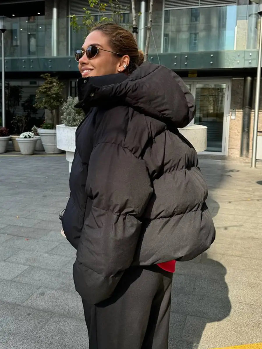 Schwarze wattierte Pufferjacke mit Kapuze mit einem warmen, isolierenden Design, geeignet für kaltes Wetter.
