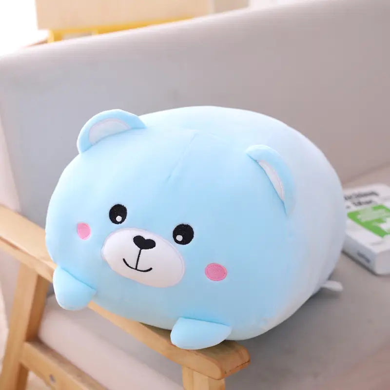 A soft light blue plush animal pillow shaped like a bear with pink cheeks and a white snout designed as a cartoon doll for kids.