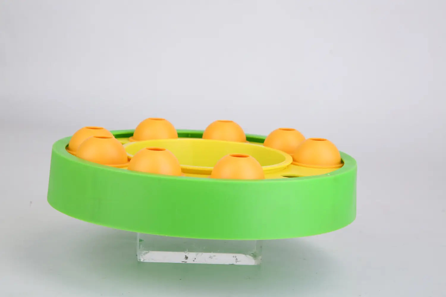 Leuchtend grün-gelbes Kunststoff-Dog-Puzzle-Futterspielzeug mit orangefarbenen kugelförmigen Fächern, ausgelegt als langsames Füttern und interaktives Spielzeug.