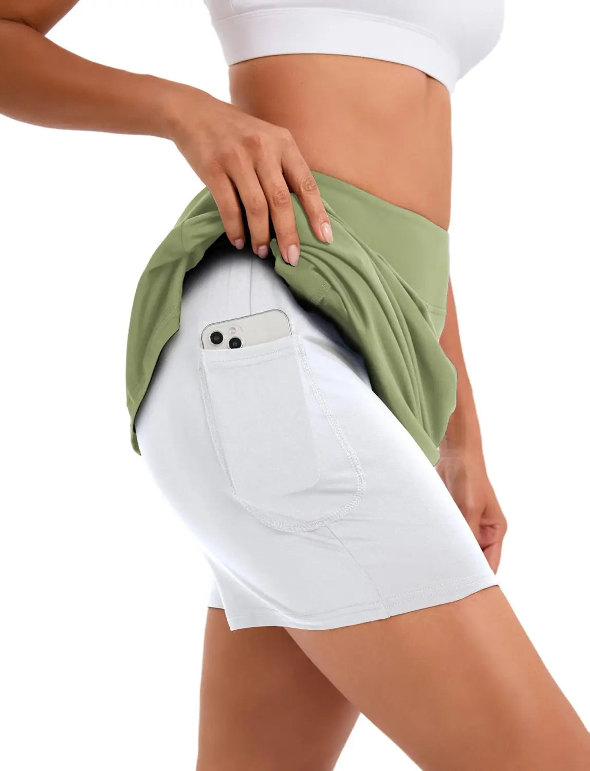 white athletic shorts with side pocket holding a smartphone paired with an olive green fabric wrap worn as part of the paisley high-waisted athletic tennis skirt ensemble