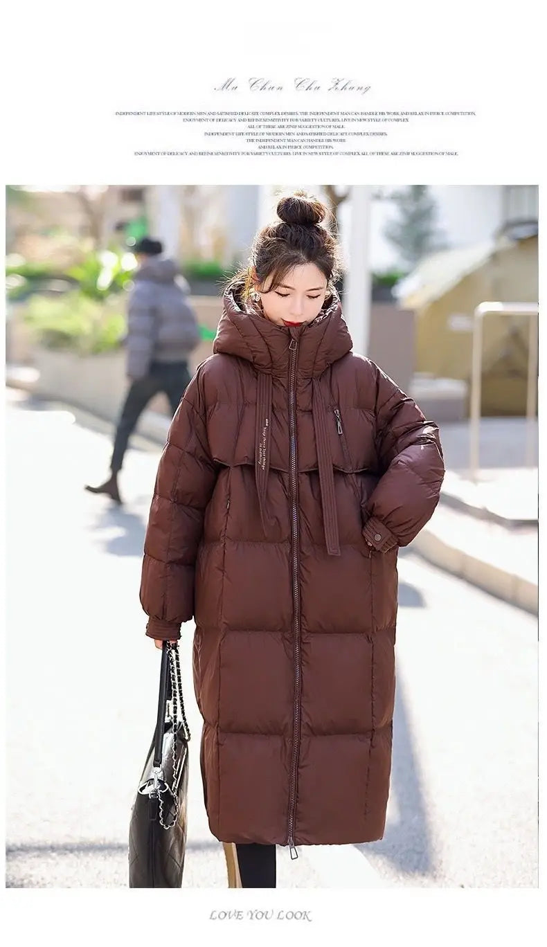 A long brown hooded puffer coat for women featuring a front zipper and quilted design.
