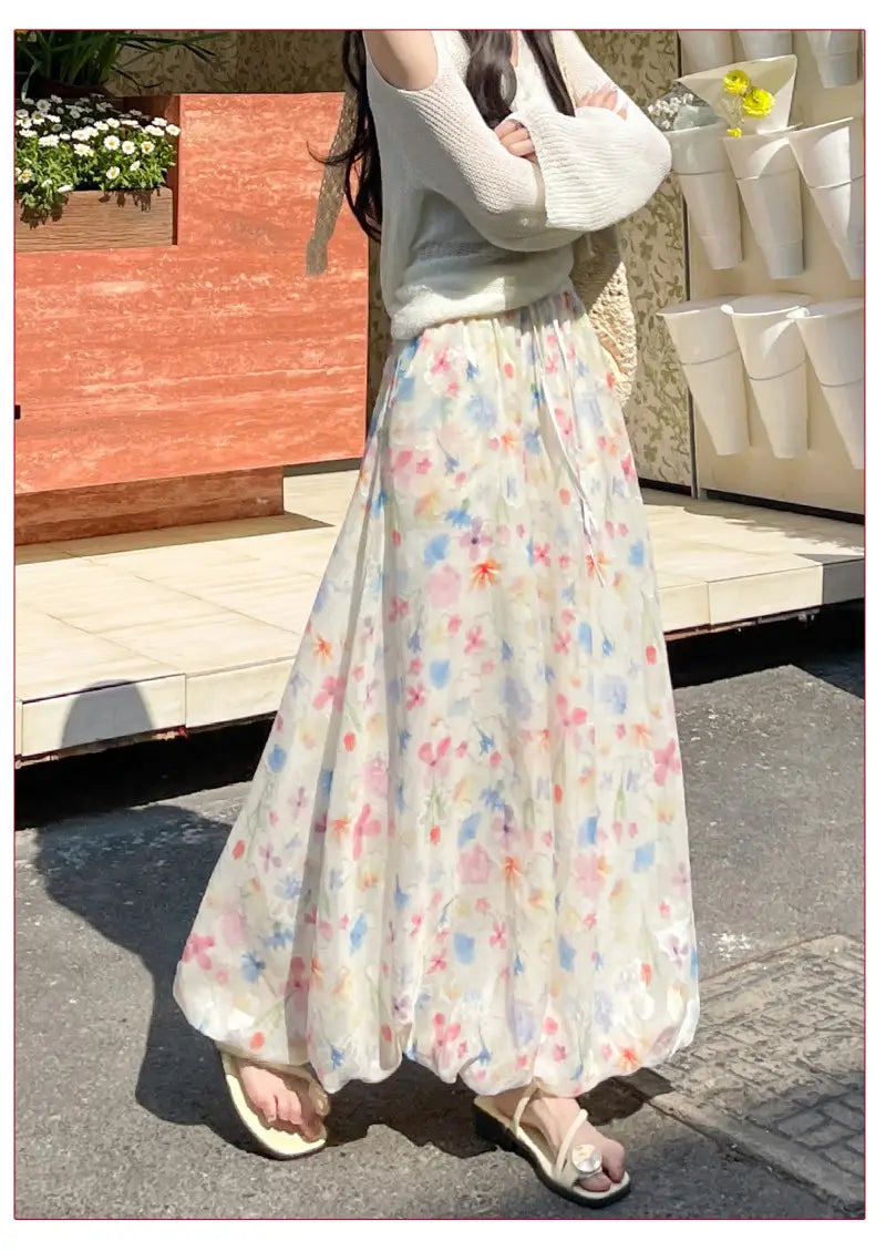 Falda midi con estampado floral, con un diseño maxi floral pastel que fluye en tejido ligero, con delicadas flores en tonos rosa, azul y amarillo, sobre una base color marfil.