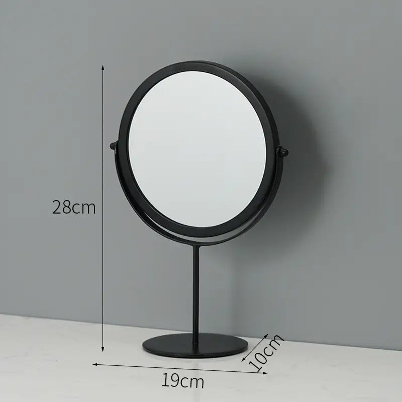 Black round vanity mirror with a sleek metal frame and stand designed for use as a makeup desk mirror.