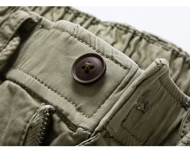 Bouton marron foncé sur un short cargo en coton pour hommes vert olive à coupe ample et taille à cordon de serrage.