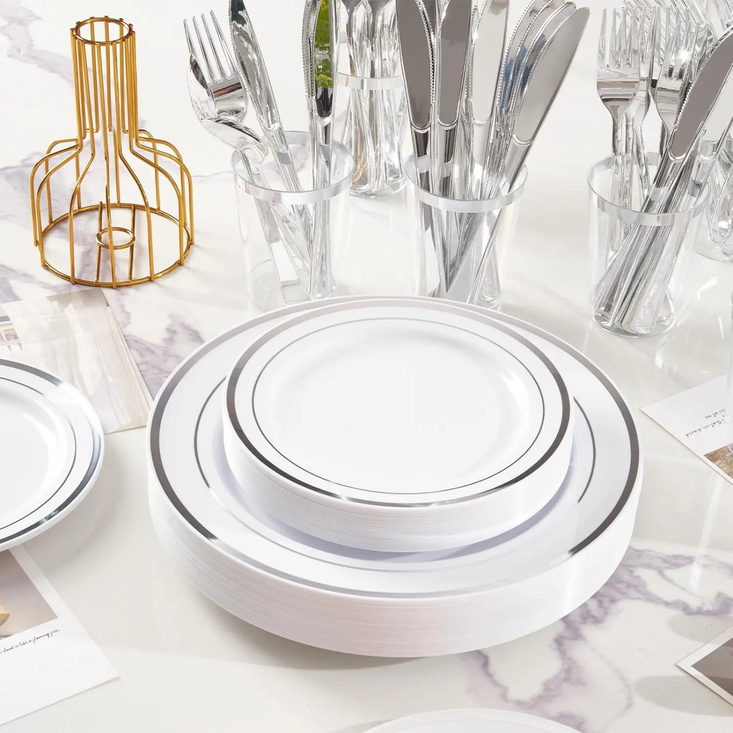 Stack of white plastic plates with silver rims from a plastic tableware set designed for 50 guests.