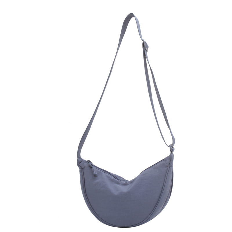 A sleek minimalist gray nylon dumpling messenger bag with a curved silhouette and adjustable crossbody strap.