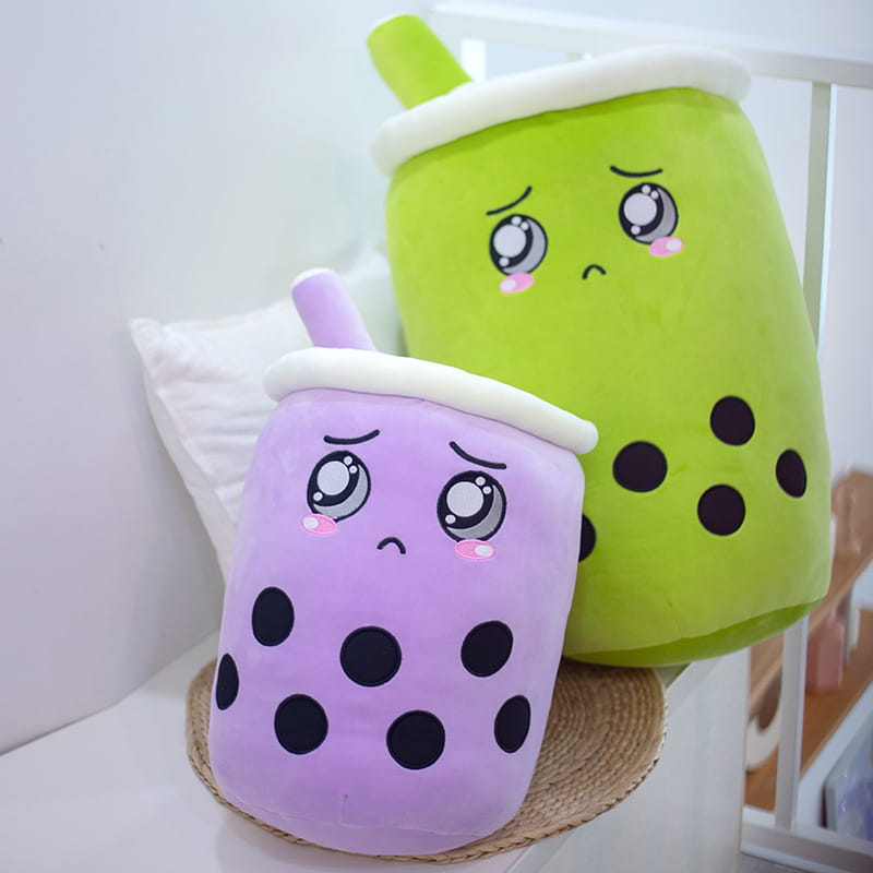 coussin moelleux boba tea kawaii en forme de lait de thé aux fruits, en violet et vert, avec des perles de tapioca noires, des sommets en mousse blanche et des adorables visages brodés.