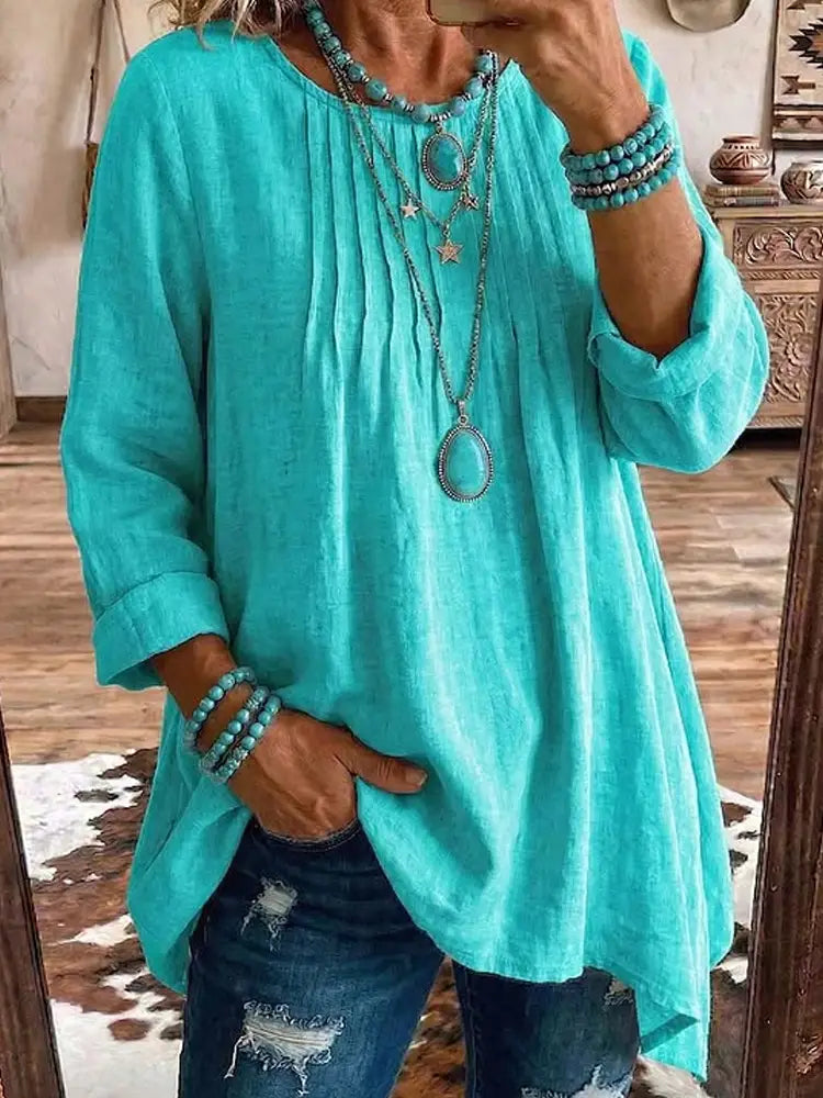 Tunique en lin turquoise souple et fluide, ample, décontractée, à manches longues, avec manches retroussées et coupe détendue.