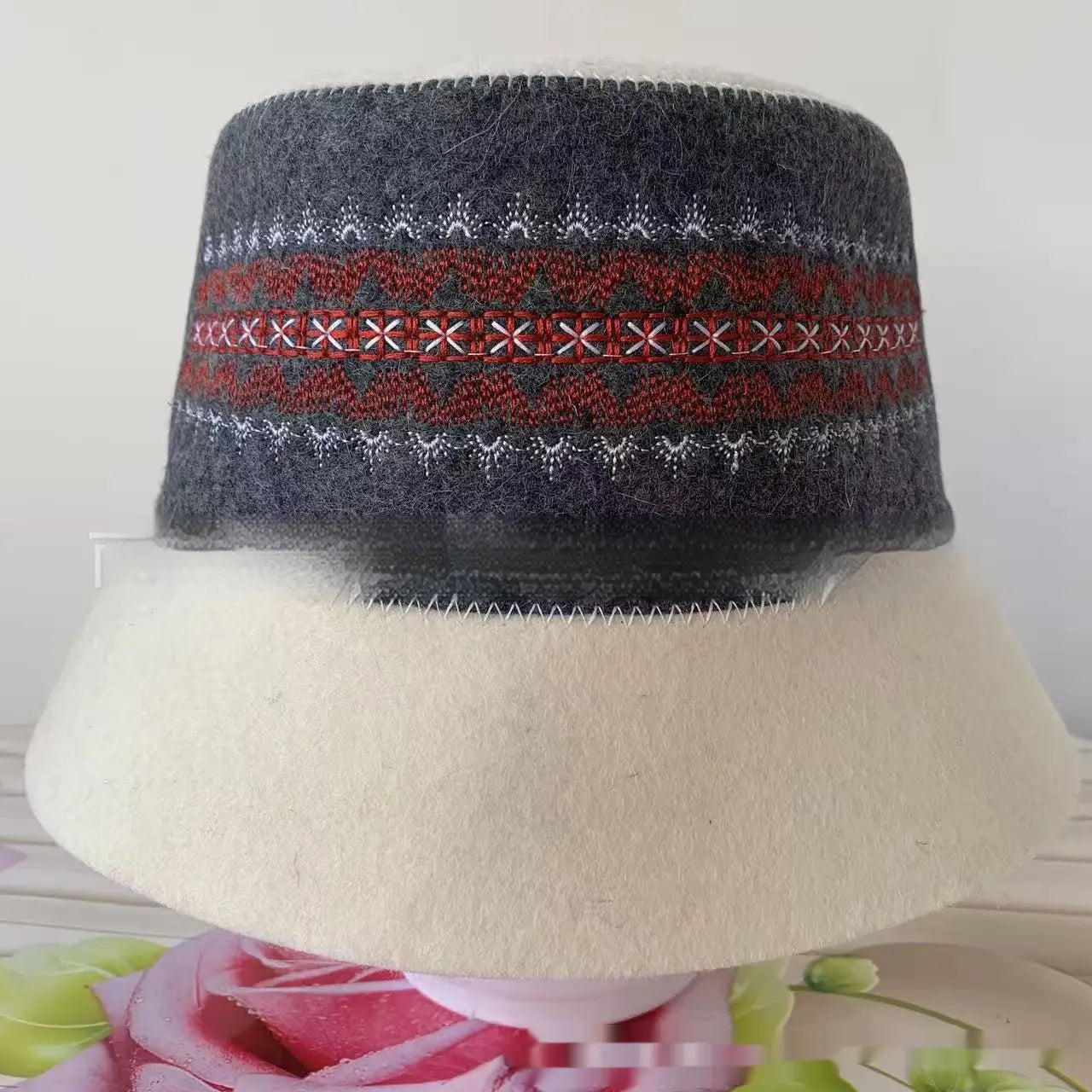 A dark gray wool felt sauna cap bucket hat with a decorative band featuring red green and white geometric embroidery.