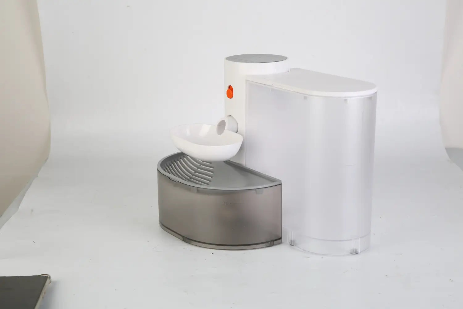 Fontaine à eau intelligente pour animal de compagnie blanche et argentée, avec une base incurvée moderne et élégante, et un voyant indicateur orange, conçue comme un bol sans fil rechargeable de 3 litres.