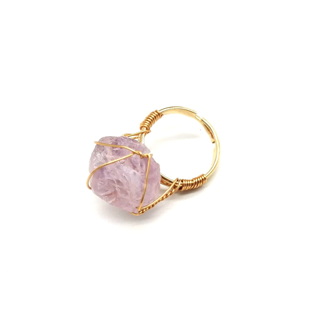 A handcrafted raw gemstone gold wire wrapped adjustable ring featuring a delicate gold wire wrapped design with a raw faceted lavender amethyst stone.