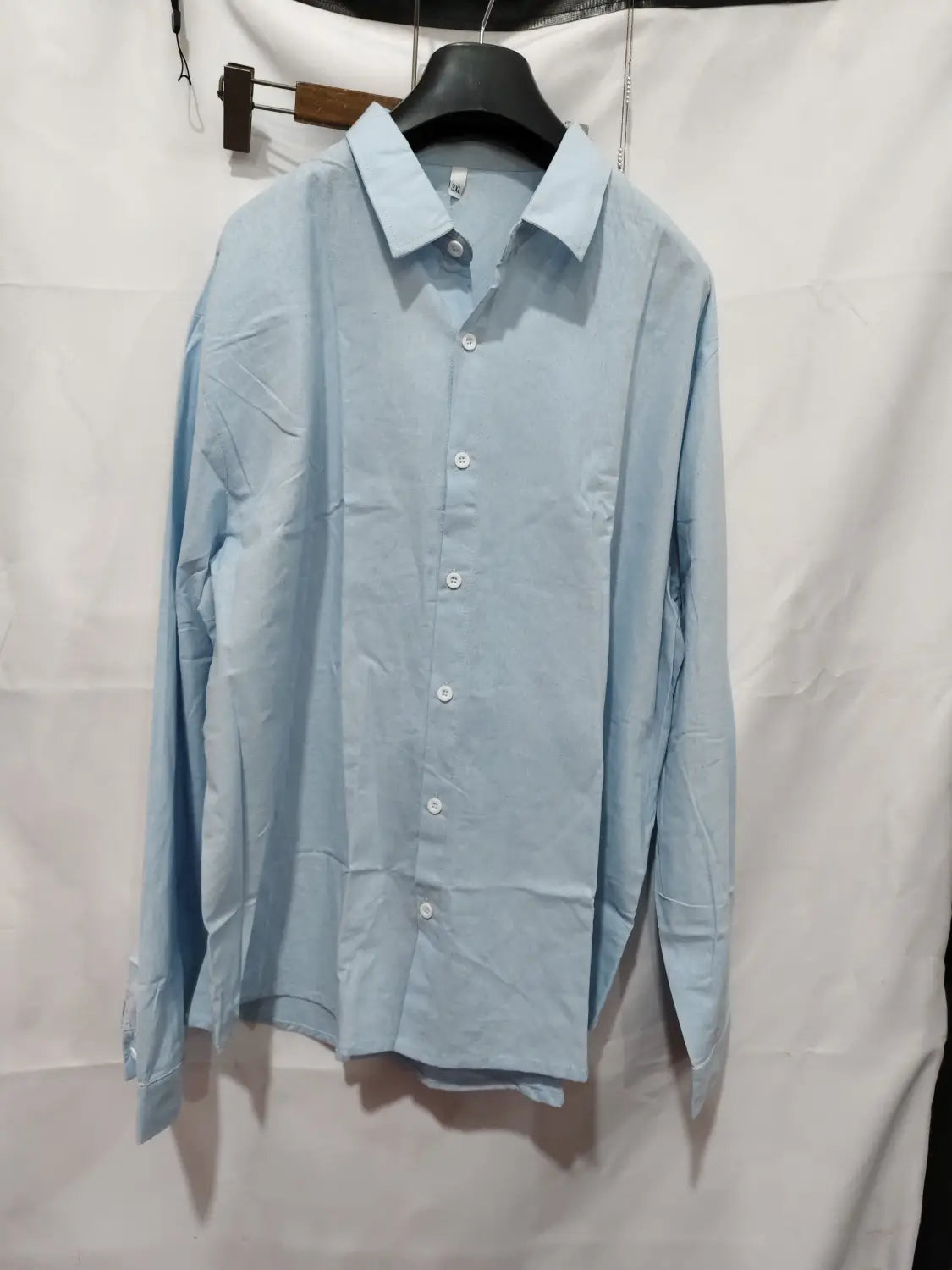 Light blue men linen casual button down shirt with long sleeves hanging on a black hanger.