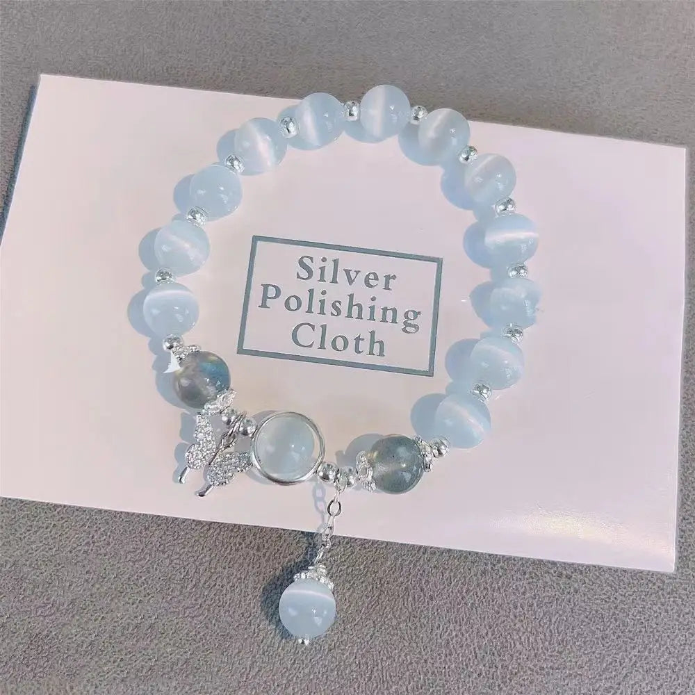 A delicate crystal butterfly cat’s eye bead bracelet featuring translucent light blue beads with silver accents and a matching dangling pendant charm.